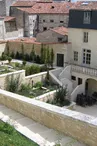 Jardin en terrasse, bordure en pierre, le bas du bâtiment est formé d'arches
