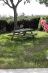 table de pique-nique dans le jardin entouré de buisson et de roses trémières